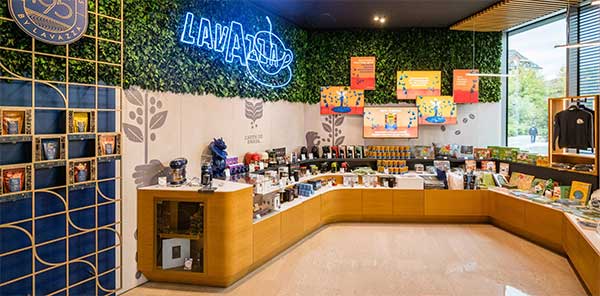 Lavazzaの歴史  すべては1895年に、ルイージ・ラヴァッツァ(Luigi Lavazza)がトリノのサン・トンマーゾ通りに初めて「ラヴァッツァ雑貨店(Drogheria Lavazza)」を開いたことから始まりました。ルイージ・ラヴァッツァは、革新精神にあふれ、創造性と仕事への情熱を持った人物でした。  ラヴァッツァのブレンドが誕生した経緯 ルイージは、さまざまなコーヒー豆の起源や特徴を見出し、それらをブレンドする技術を磨き、顧客の好みに応えるコーヒーを作り上げました。ブラジルへの旅を通じて、彼は大きな変革の時代に、コーヒーの可能性を見抜きました。今日私たちが飲んでいるラヴァッツァのコーヒーは、ルイージがさまざまな地域からのコーヒー豆を組み合わせて生み出したものです。  1927年：小さな店から企業へ ルイージ・ラヴァッツァは、妻エミリア(Emilia)と子供たちと共に会社を設立しました。当時、会社の資本金は150万リラでした。 この時期、ラヴァッツァは香りを保つために「ペルガミン(Pergamin)」という二重層の紙包装を導入し、家庭向けに大量のコーヒーを販売するための最初のステップを踏み出しました。  1947年 – 戦後の復興 ラヴァッツァは第二次世界大戦とコーヒー禁輸措置を乗り越えました。1947年には、ミラノの「エアロスタジオ・ボルギ(Aerostudio Borghi)」によって、最初のラヴァッツァのロゴが作られ、中心の「A」が今でも象徴的なデザインとなっています。  1955年 – 伝説の「ラヴァッツァ・ブレンド(Miscela Lavazza)」の誕生 1955年、ベッペの息子であるエミリオ・ラヴァッツァが会社に入り、伝説の「ラヴァッツァ・ブレンド」を生み出しました。「ラヴァッツァ、カップの中の楽園(Lavazza Paradiso in tazza)」という最初のスローガンが新聞やラジオで広まりました。  1957年 – イタリア最大のコーヒー企業へ イタリアの経済成長とともに、ラヴァッツァはイタリア最大のコーヒー企業となり、ヨーロッパでのリーダーシップへの道を歩み始めました。  1965年 – 製造工場新設 Lavazzaはトリノ郊外のセッティモ・トリネーゼ地区に新しい製造工場を設立し、これがヨーロッパ最大級のコーヒー焙煎・製造施設となりました。  1971年 – イノベーションで危機を克服 1970年代の経済不況期に、ラヴァッツァは新しい真空包装を導入し、クオリタ・ロッサ(Qualità Rossa)のブレンドを発売しました。1977年には、ニーノ・マンフレディ(Nino Manfredi)が16年間にわたりラヴァッツァの顔となりました。 「もっと飲めば、もっと元気になる(Più lo mandi giù e più ti tira su)」や「コーヒーは喜び、良くなければ何の喜びでもない(Il caffè è un piacere, se non è buono che piacere è?)」といった名セリフで、ブランドの認知度をさらに高めました。しかし、マンフレディはLavazzaのすべての商品を宣伝していたわけではありません。たとえば「Paulista」コーヒーは、夫婦として知られるライモンド・ヴィアネッロとサンドラ・モンダイーニが宣伝し、デカフェの「Lavazza Dek」は1988年に特別な広告が放送されました。デカフェとは、カフェインを含まない、もしくはカフェインの量を極力減らしたコーヒーのことを指します。日本ではまだあまり馴染みがないかもしれませんが、カフェインを控えたい方や、夜遅い時間にもコーヒーを楽しみたい方に向けて欧米では人気があります。Lavazzaのデカフェ商品は、通常のコーヒーと同じく豊かな味わいが特徴です。  1980年代 – 世界進出を果たす ラヴァッツァは1980年代に国際展開を始め、フランス、ドイツ、オーストリア、アメリカ、イギリスに拠点を開設しました。広告も国際的に広がり、イタリアらしい高品質なコーヒーの魅力を伝えました。  1989年 – バリスタの育成 「トレーニングセンター ラヴァッツァ(Training Center Lavazza)」を設立し、バリスタの育成や新製品の研究開発を行う拠点としました。  1990年代 – ラヴァッツァの新たな表現  1995年、エミリオ・ラヴァッツァ(Emilio Lavazza)とアルマンド・テスタ(Armando Testa)との協力で、5代目のラヴァッツァのロゴが誕生しました。また、有名シェフとの協力を始め、象徴的な「ラヴァッツァカレンダー(Calendario Lavazza)」も生まれました。  2004年 – 社会的責任への取り組み 2004年、ラヴァッツァは持続可能性を目指し、「¡ティエッラ！(¡Tierra!)」プロジェクトを開始しました。このプロジェクトを通じて、世界中のコーヒー農家の生活条件を改善し、新しい持続可能な農業技術を導入しました。]  2005年には、カバジェロ(Caballero)とカルメンシータ(Carmencita)が再び広告に登場しました。この時、イタリアのテレビ局「イタリア1（Italia 1）」でミニシリーズとして放送されました。イタリア1は、バラエティ、ドラマ、アニメなどを放送するイタリアの主要な民放テレビ局で、特に若年層に人気があります。このミニシリーズは、過去の人気キャラクターに新たな命を吹き込む試みとして話題を呼びました。  Lavazzaの革新は技術面にも及び、2015年には、国際宇宙ステーションのために「ISSpresso」マシンを開発。イタリアの宇宙飛行士サマンサ・クリストフォレッティ(Samantha Cristoforetti)がこのマシンを使用し、宇宙空間でのコーヒー体験を提供しました。  トリノのボルゴ・アウローラ(Borgo Aurora)地区に「Nuvola Lavazza」という新しい本社を設立。これにはLavazzaの歴史やコーヒー文化を紹介する博物館(Museo Lavazza)も併設されています。Lavazzaは、伝統を守りつつも常に革新を続ける、世界的なコーヒーブランドとして成長を続けています。  また、Lavazzaの海外広告キャンペーンでは、著名な写真家を起用していることでも知られています。ジャン＝バティスト・モンディーノ、デヴィッド・ラシャペル、ヘルムート・ニュートン、アルバート・ワトソン、アニー・リーボヴィッツなどの著名なアーティストが手掛けた作品が、Lavazzaの国際的な広告キャンペーンを飾り、Lavazzaカレンダーでもその芸術的な価値が高く評価されています。さらに、Lavazzaは2020年のF1世界選手権でウィリアムズF1の公式パートナーにもなりました。